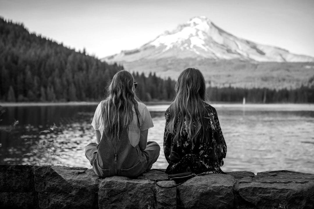 women sitting on rock near body of water women sitting on rock near body of water