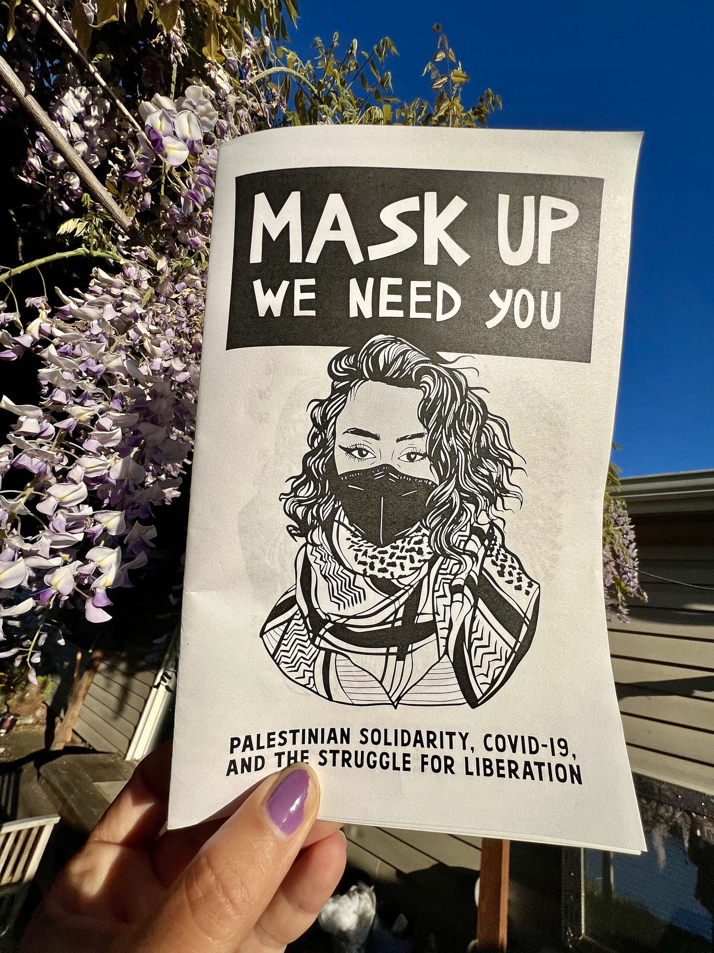 A photograph of a hand holding a zine against a blossoming spring plant and a clear blue sky. A photograph of a hand holding a zine against a blossoming spring plant and a clear blue sky.