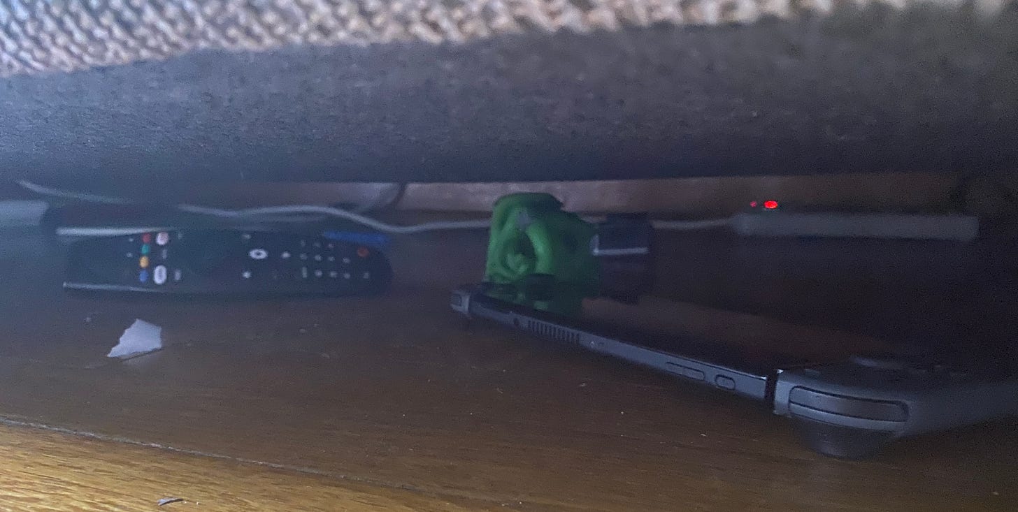 TV Remote and Handheld Switch Console Under Couch (Photo by Author)