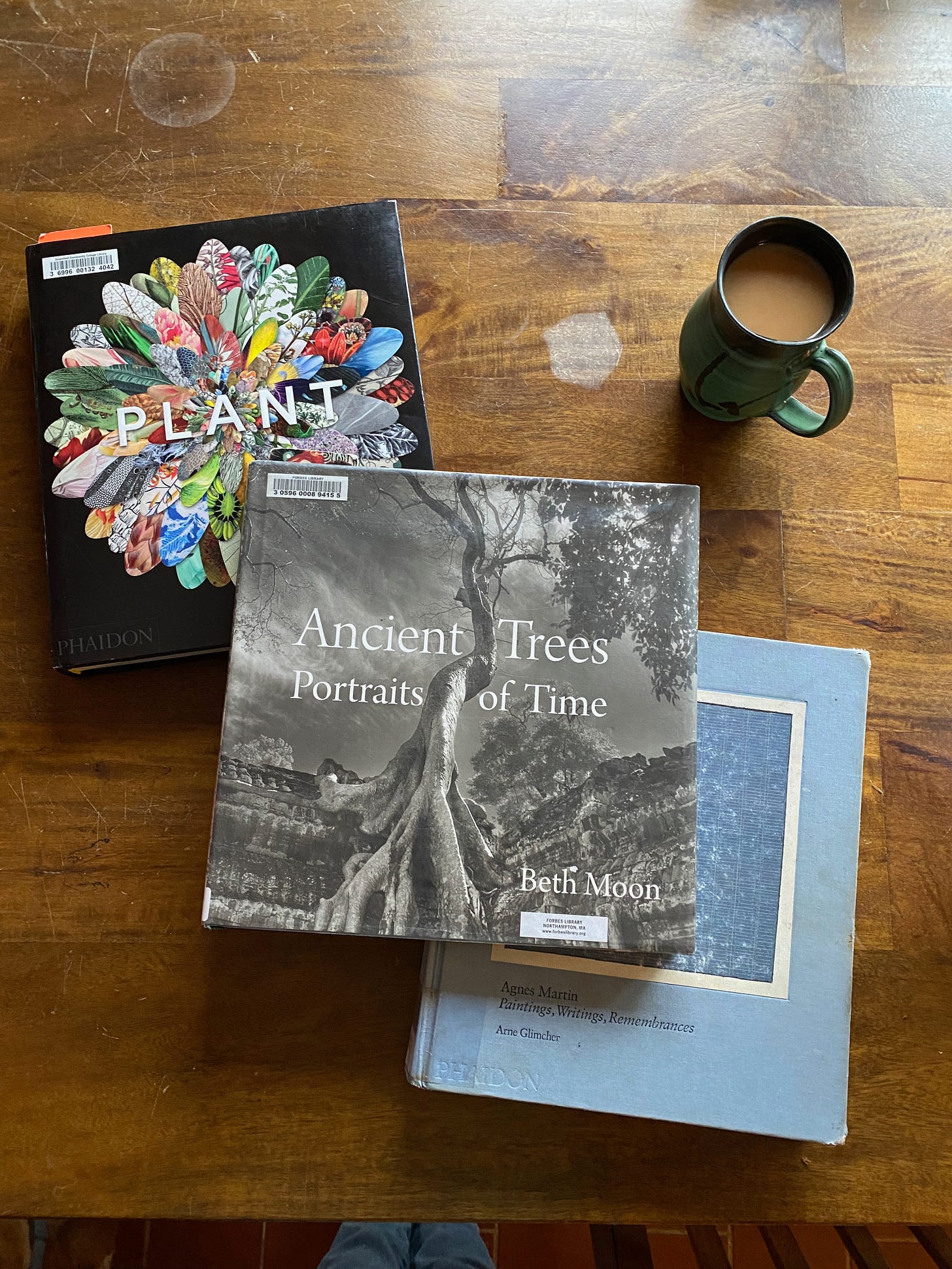Three large art/photo books on a table next to a mug of tea.