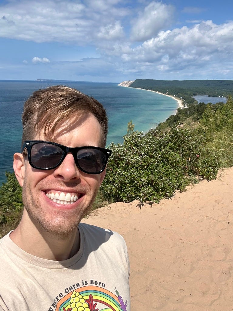 Photo of Martin smiling with sand dunes and Lake Michigan in the backgrounds