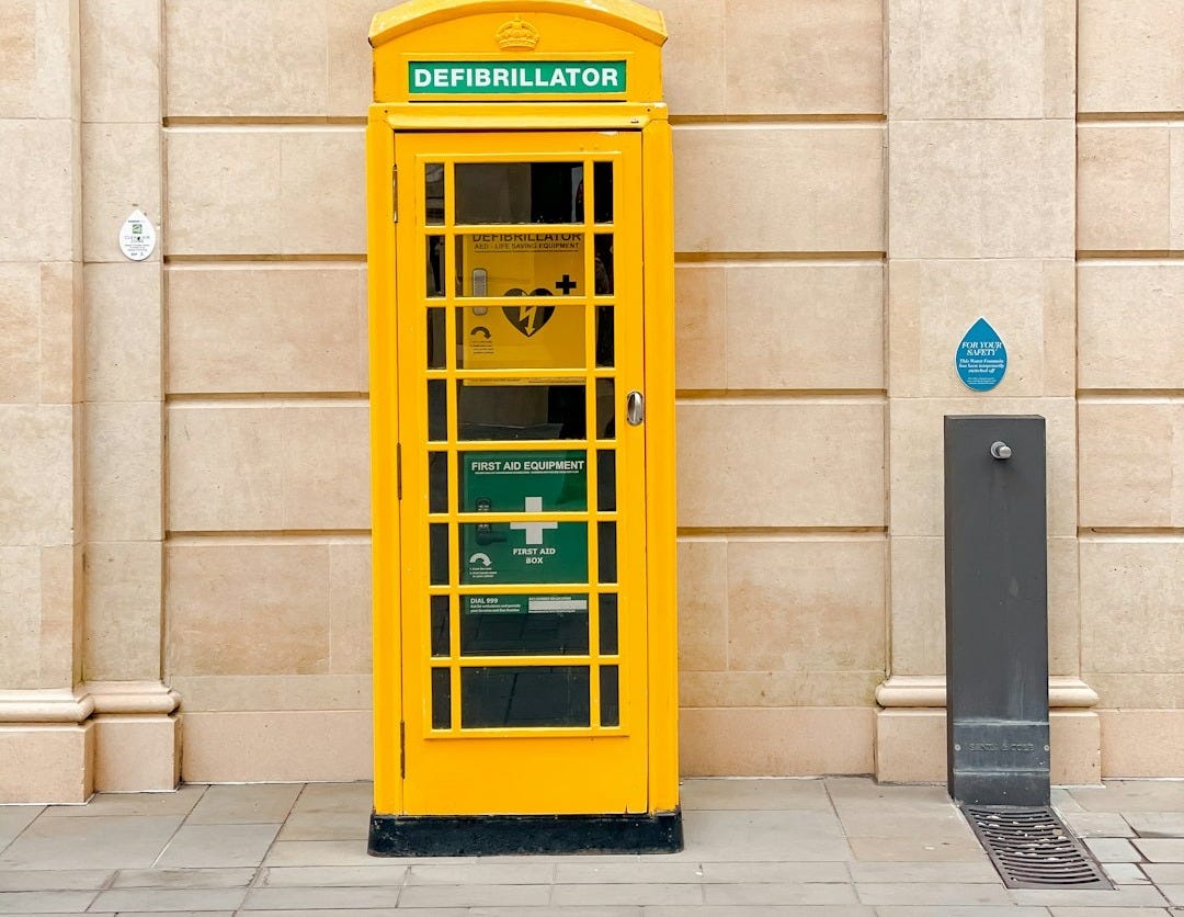 yellow telephone booth beside beige concrete building yellow telephone booth beside beige concrete building