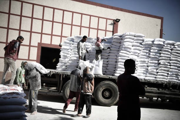 Personnel distribute flour to Palestinian families, who left their homes and took refuge in Rafah city under hard conditions, as Israeli attacks...