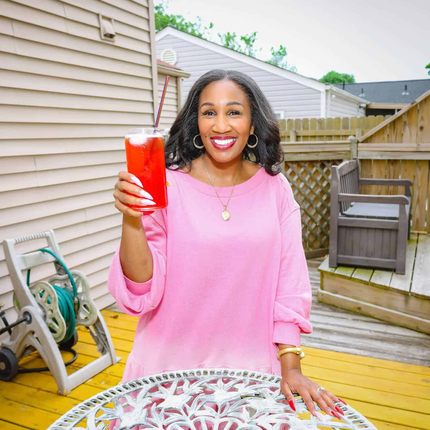 Shaunda Necole holding a bright red Juneteenth drink outdoors, representing the red beverage tradition in Black holiday celebrations and soul food culture at The Soul Food Pot®