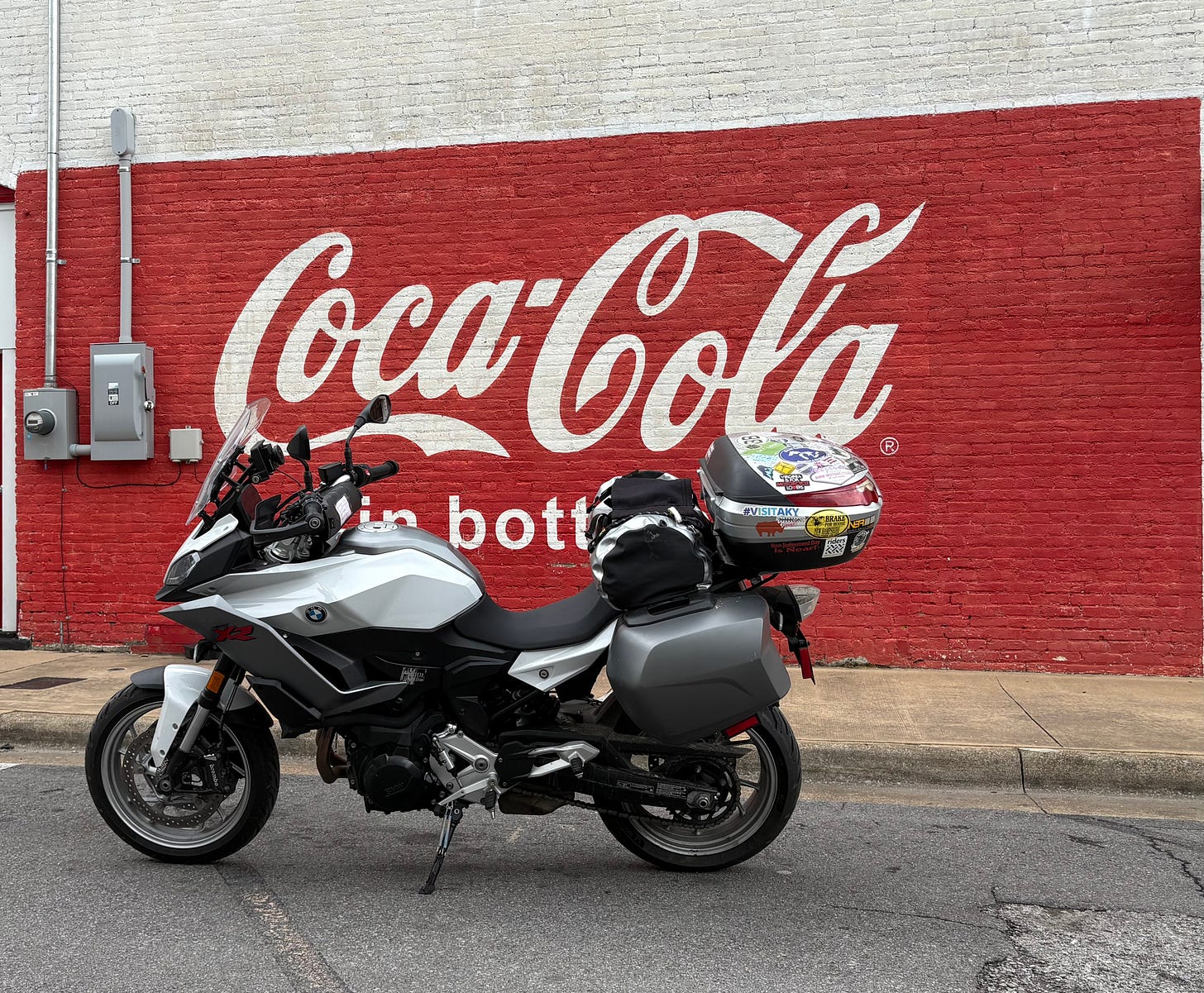 BMW motorcycle parked in front of Coca-Cola mural