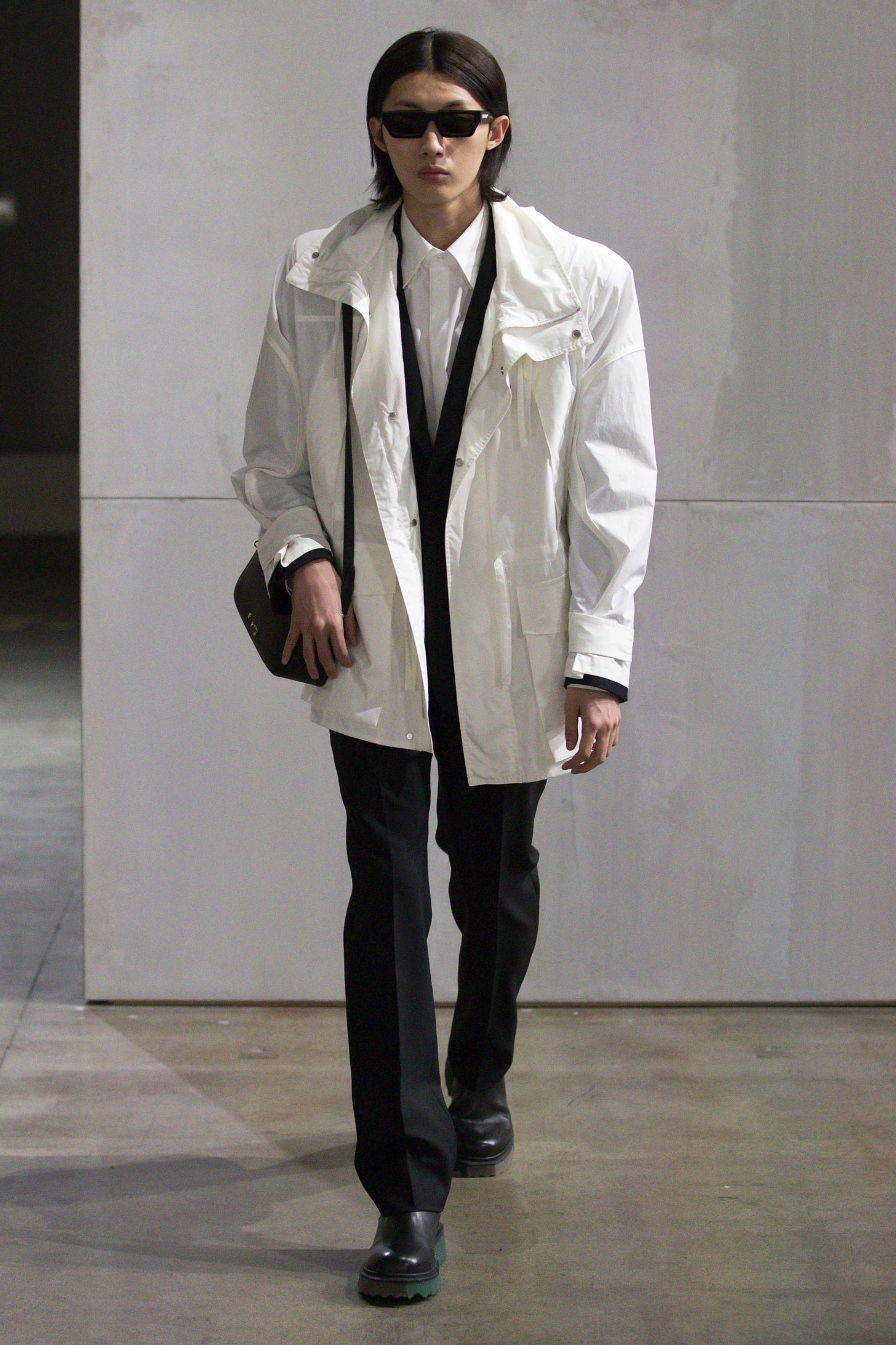 Image may contain Clothing Apparel Coat Sunglasses Accessories Accessory Human Person Overcoat Sleeve and Footwear
