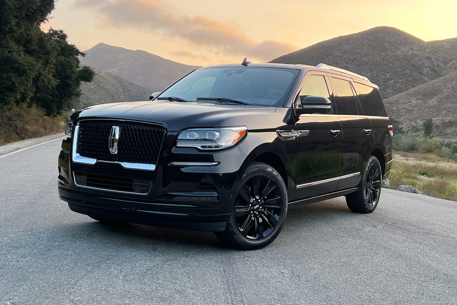 A black 2023 Lincoln Navigator parked on a road in the mountains at sunset.