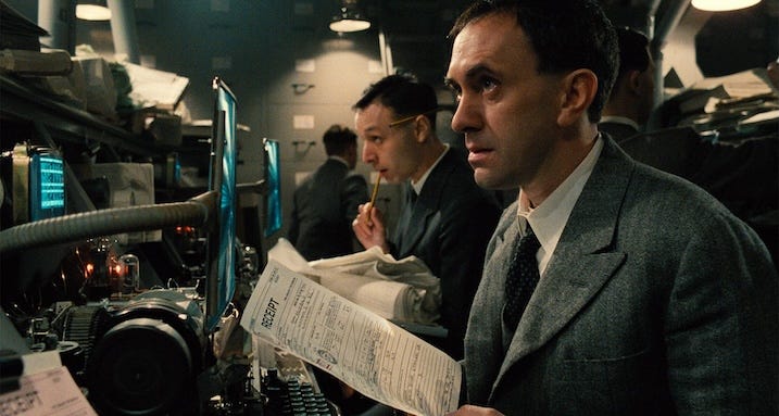 Office bureaucracy still — Jonathan Pryce as Sam Lowry works amid a maze of paperwork and ducts in Brazil (1985).