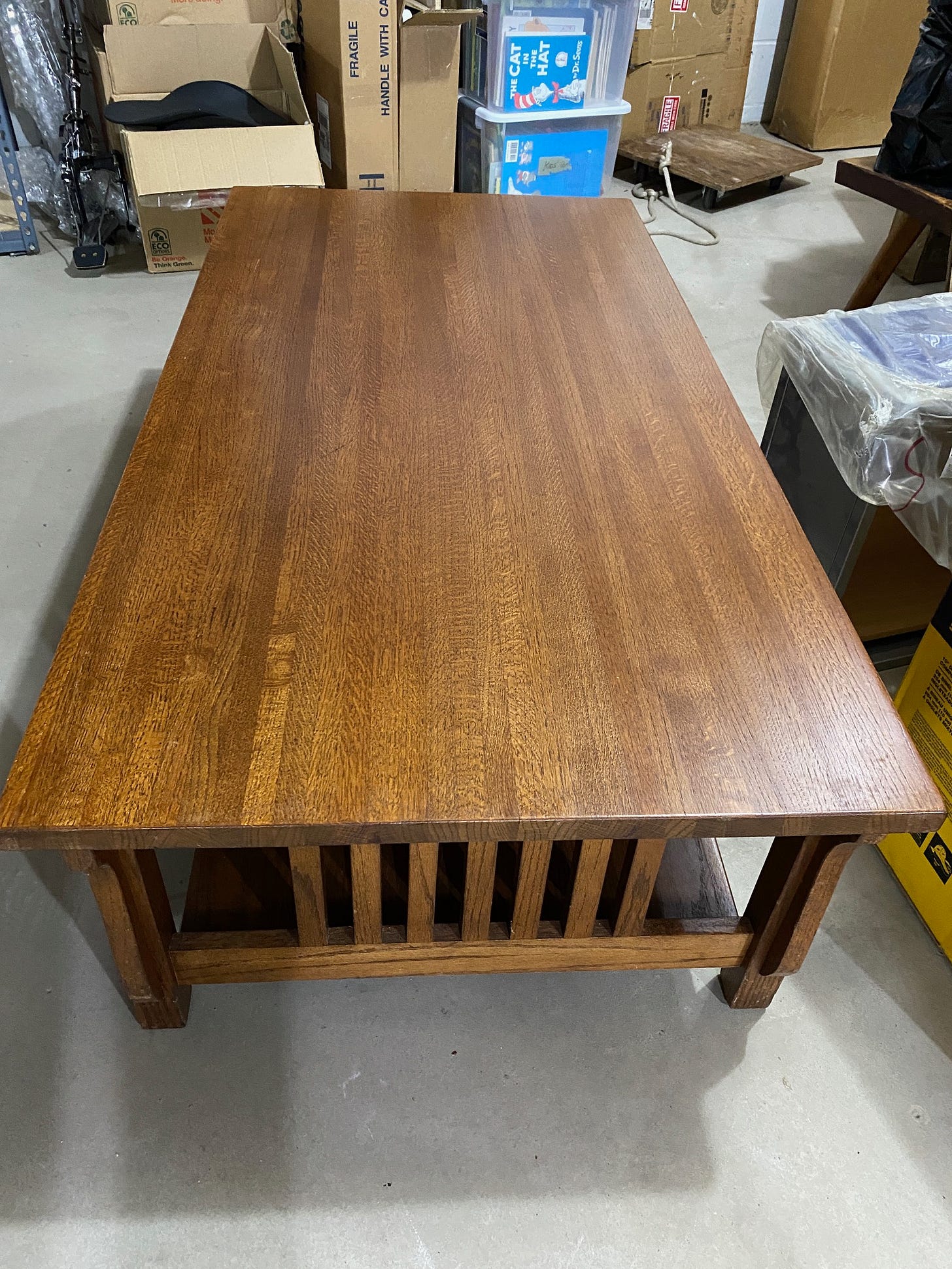 Mission style coffee table in dark oak in a basement with boxes and other random things on either side of it.