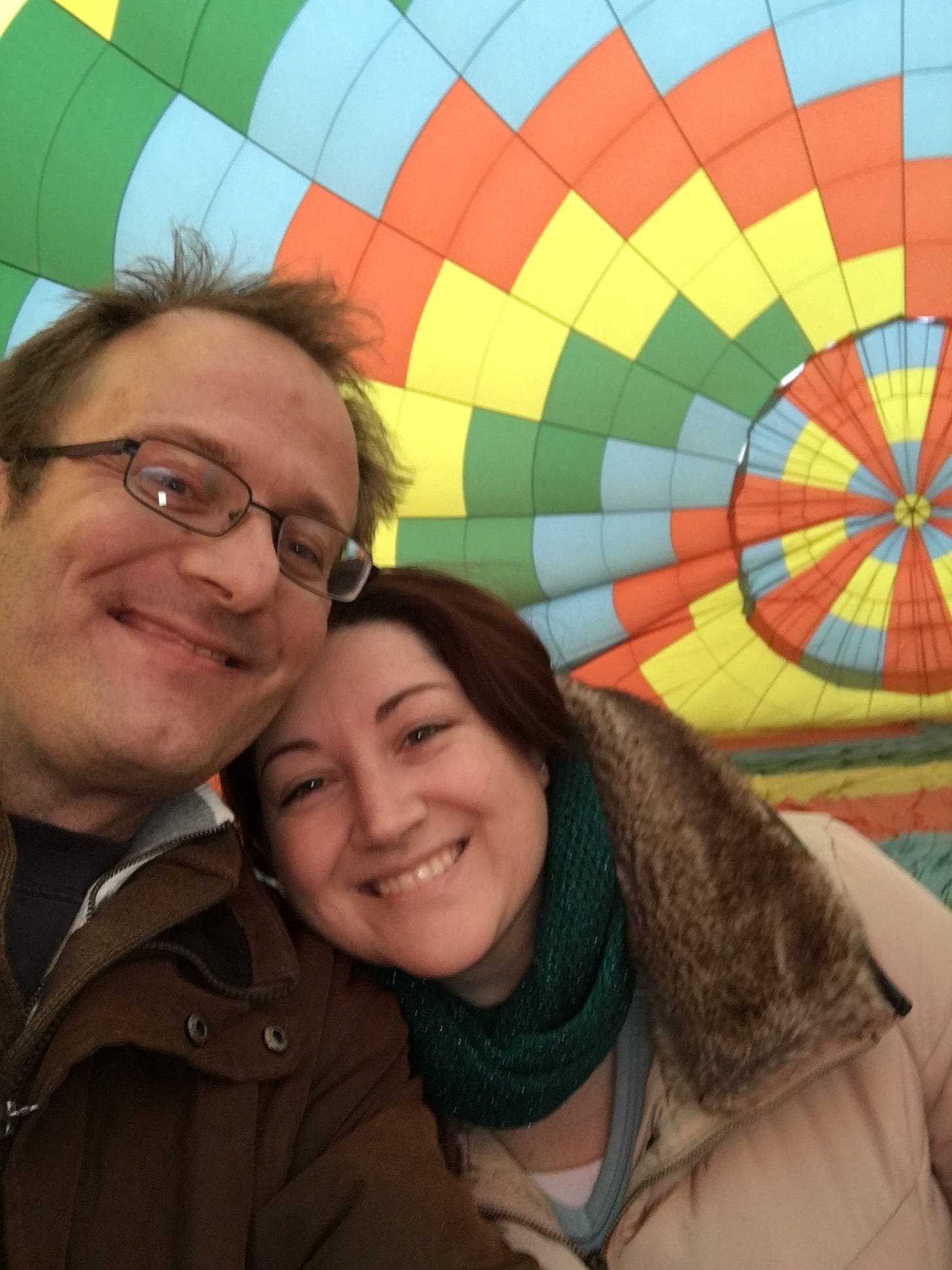 Author Alicia Dearn with her husband in front of an inflating hot air balloon.