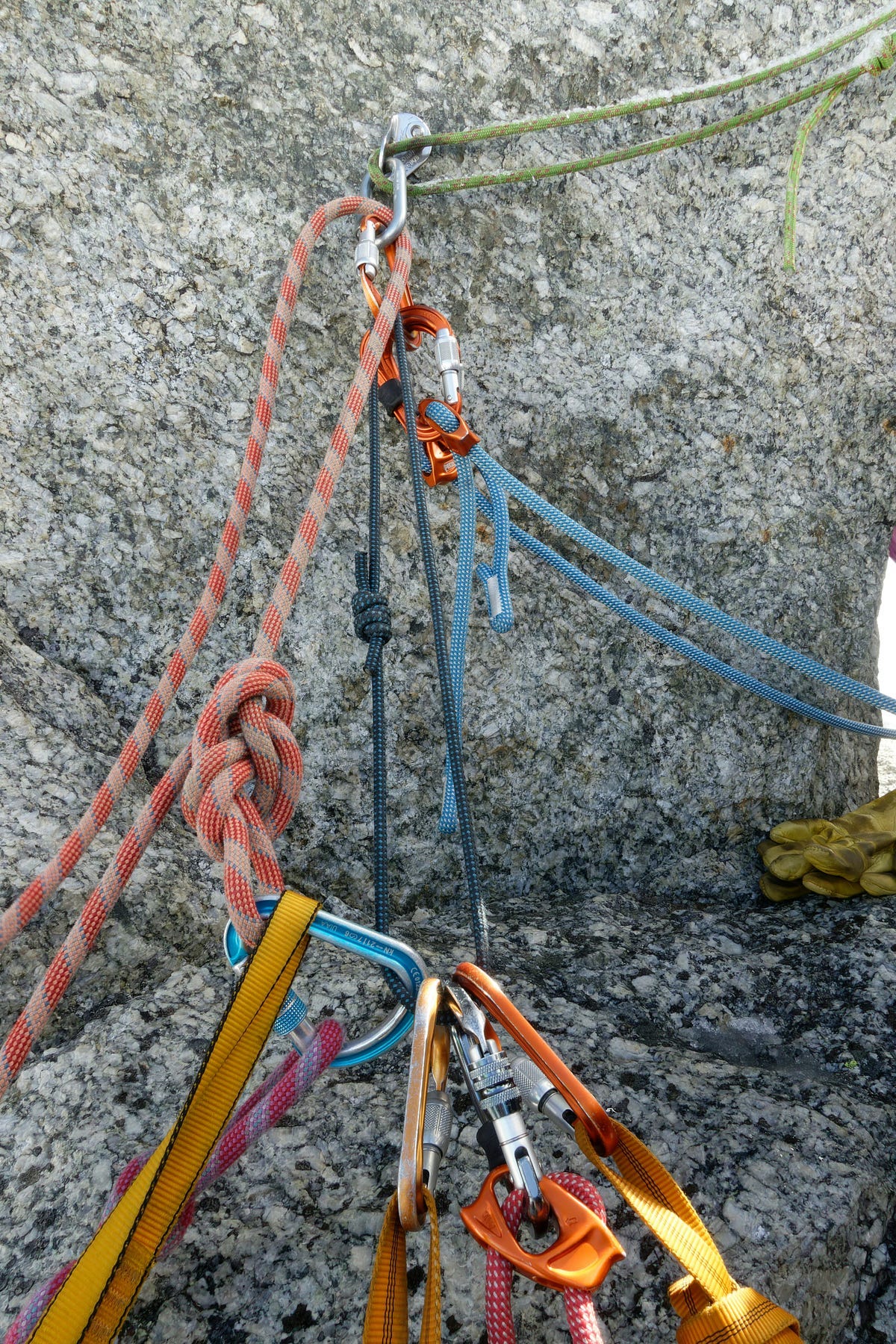 Bright multi-colored climbers’s ropes tied and tethered to a cliff’s gray stone face.