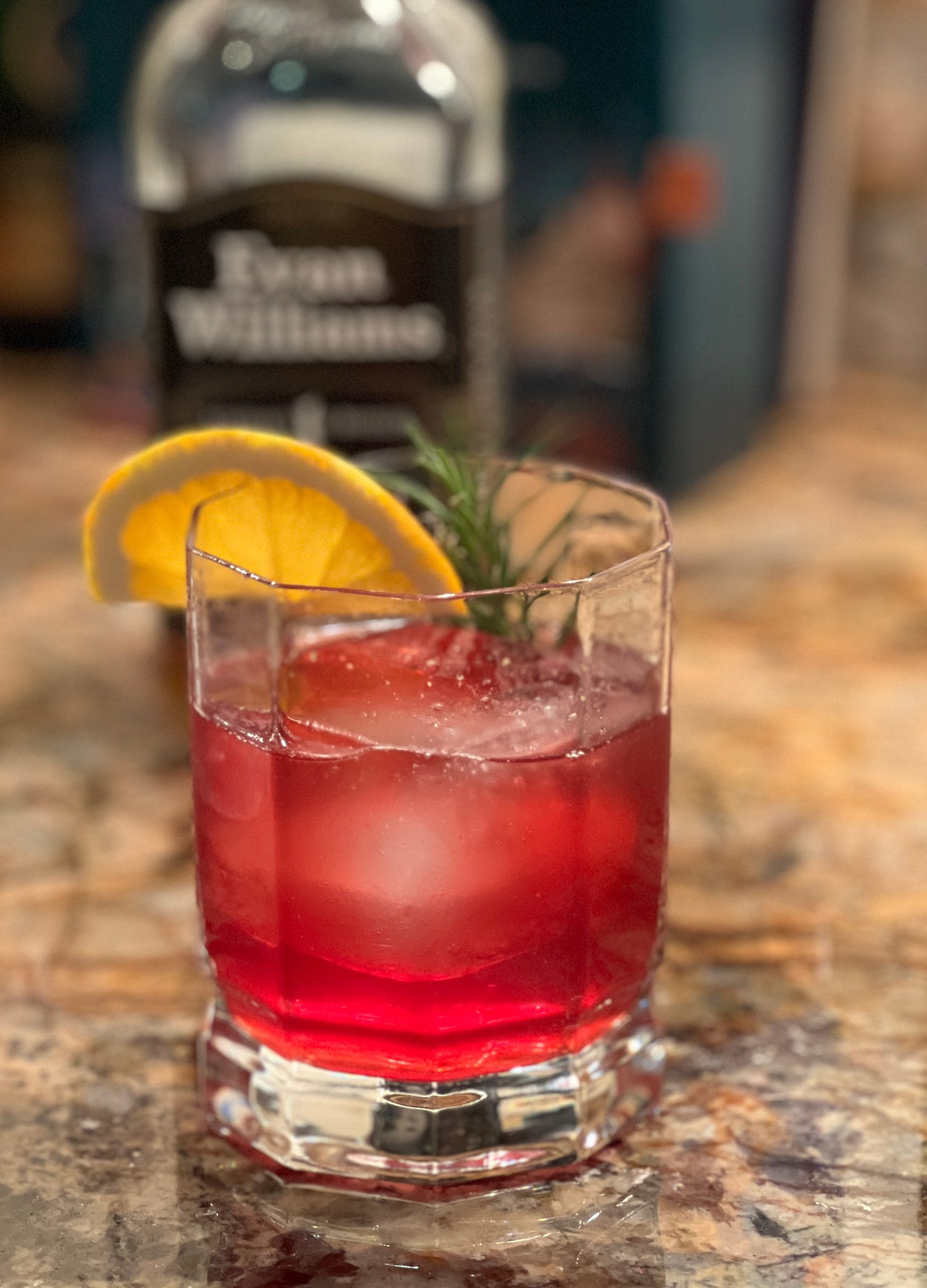 Cranberry bourbon cocktail with an orange and rosemary garnish. Cranberry bourbon cocktail with an orange and rosemary garnish.