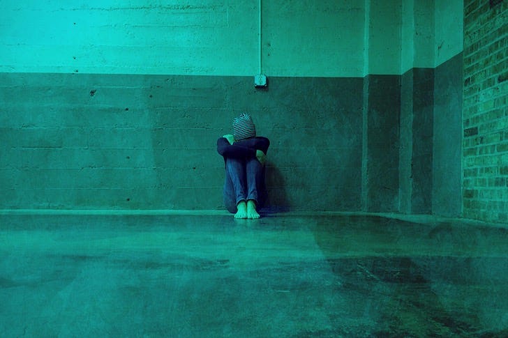 A person in despair sits in a bare room
