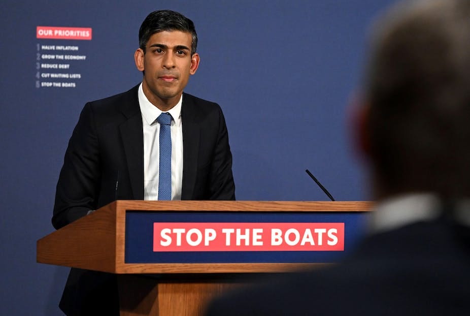 Prime Minister Rishi Sunak stands at a podium that reads 'stop the boats' on a red banner Prime Minister Rishi Sunak stands at a podium that reads 'stop the boats' on a red banner