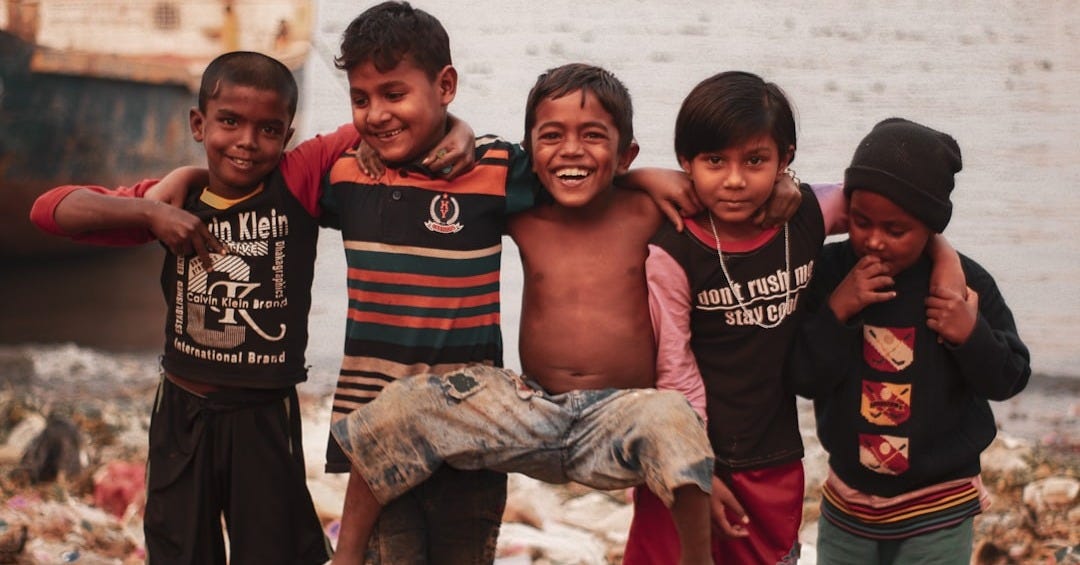 3 boys and 2 girls standing on brown sand during daytime 3 boys and 2 girls standing on brown sand during daytime
