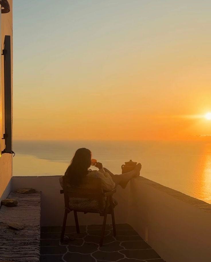 This may contain: a woman sitting in a chair on top of a balcony next to the ocean at sunset This may contain: a woman sitting in a chair on top of a balcony next to the ocean at sunset
