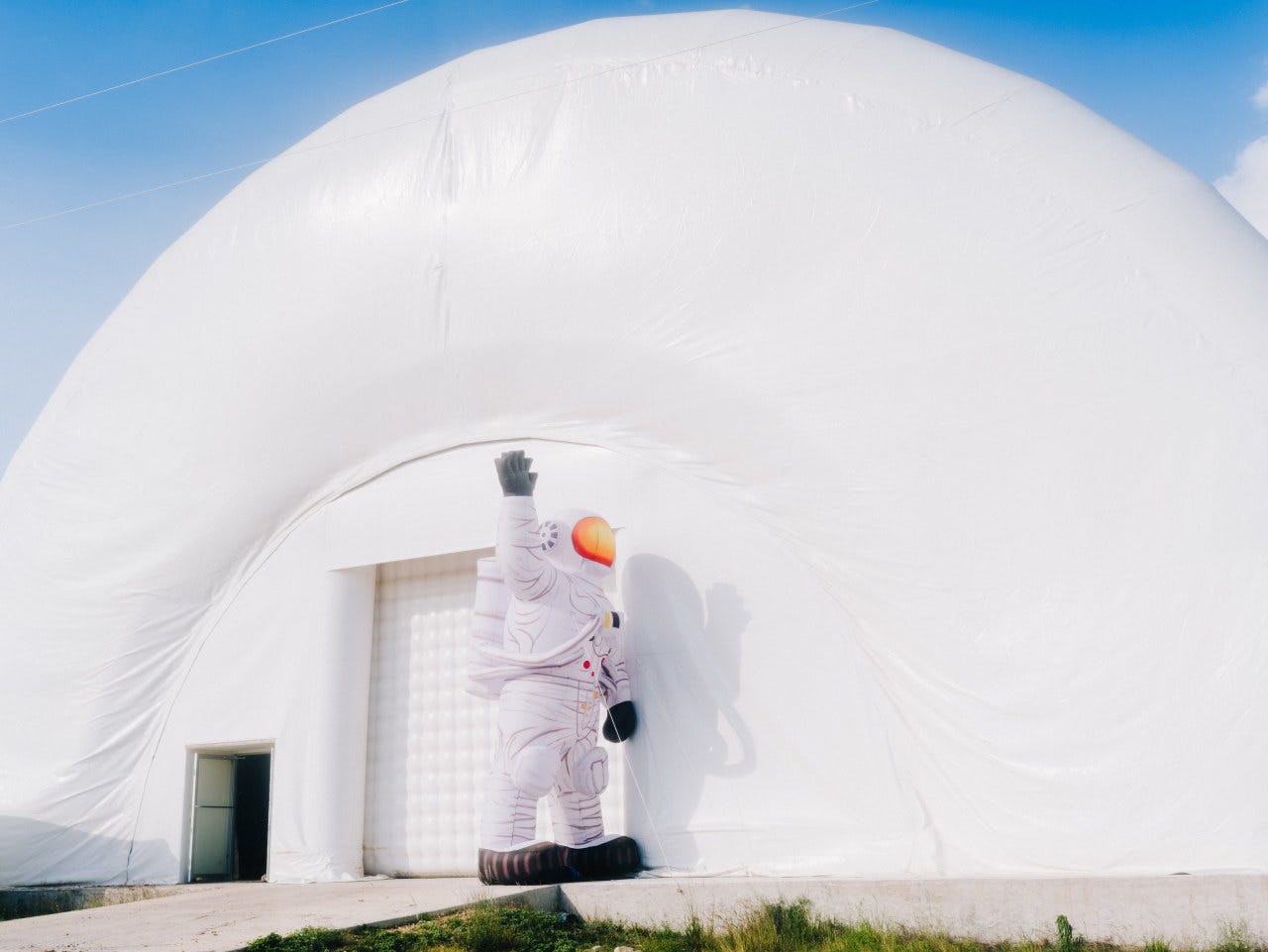 An inflatable astronaut outside of the Cuby, an inflatable building, at Proto-Town.
