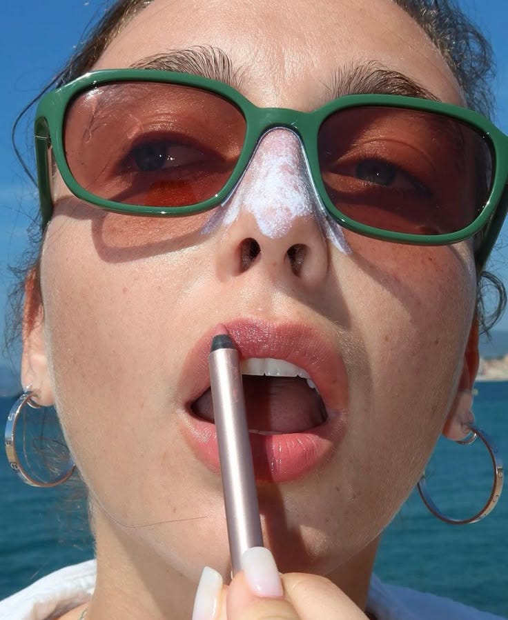 This may contain: a woman wearing glasses and holding a pencil in her mouth