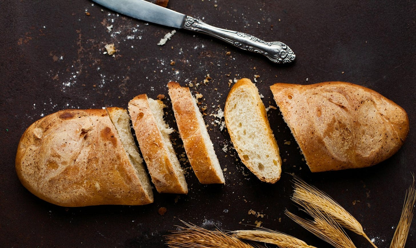 sliced of baked bread beside stainless steel bread knife sliced of baked bread beside stainless steel bread knife