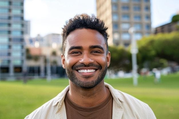 Photo handsome mixed race man smiling in front of a green park facing the camera Photo handsome mixed race man smiling in front of a green park facing the camera