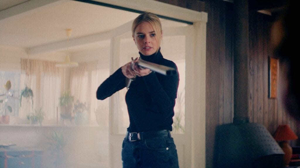Samara Weaving in black holding a shotgun pointed towards viewer Samara Weaving in black holding a shotgun pointed towards viewer