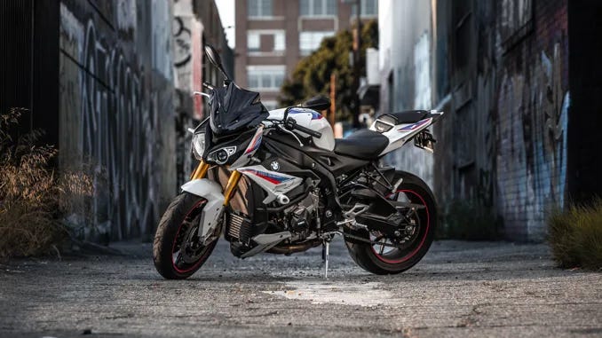 A red, white and black motorbike it parked side on in an alleyway.