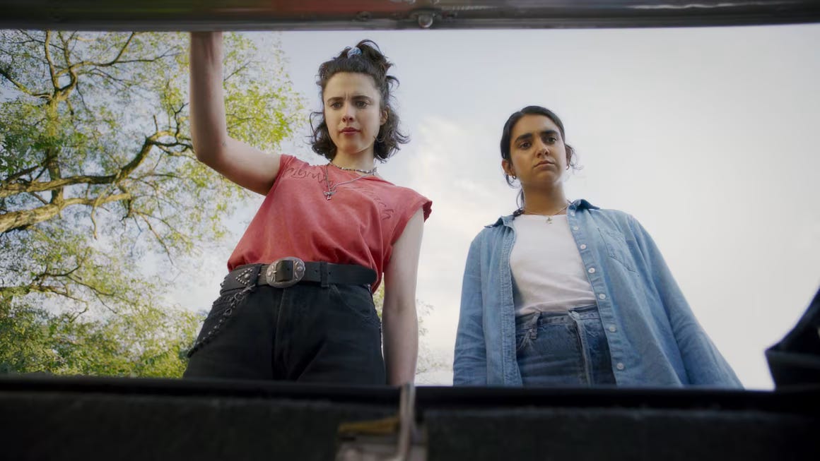 two young women, one white and one south asian, looking into the trunk of a car
