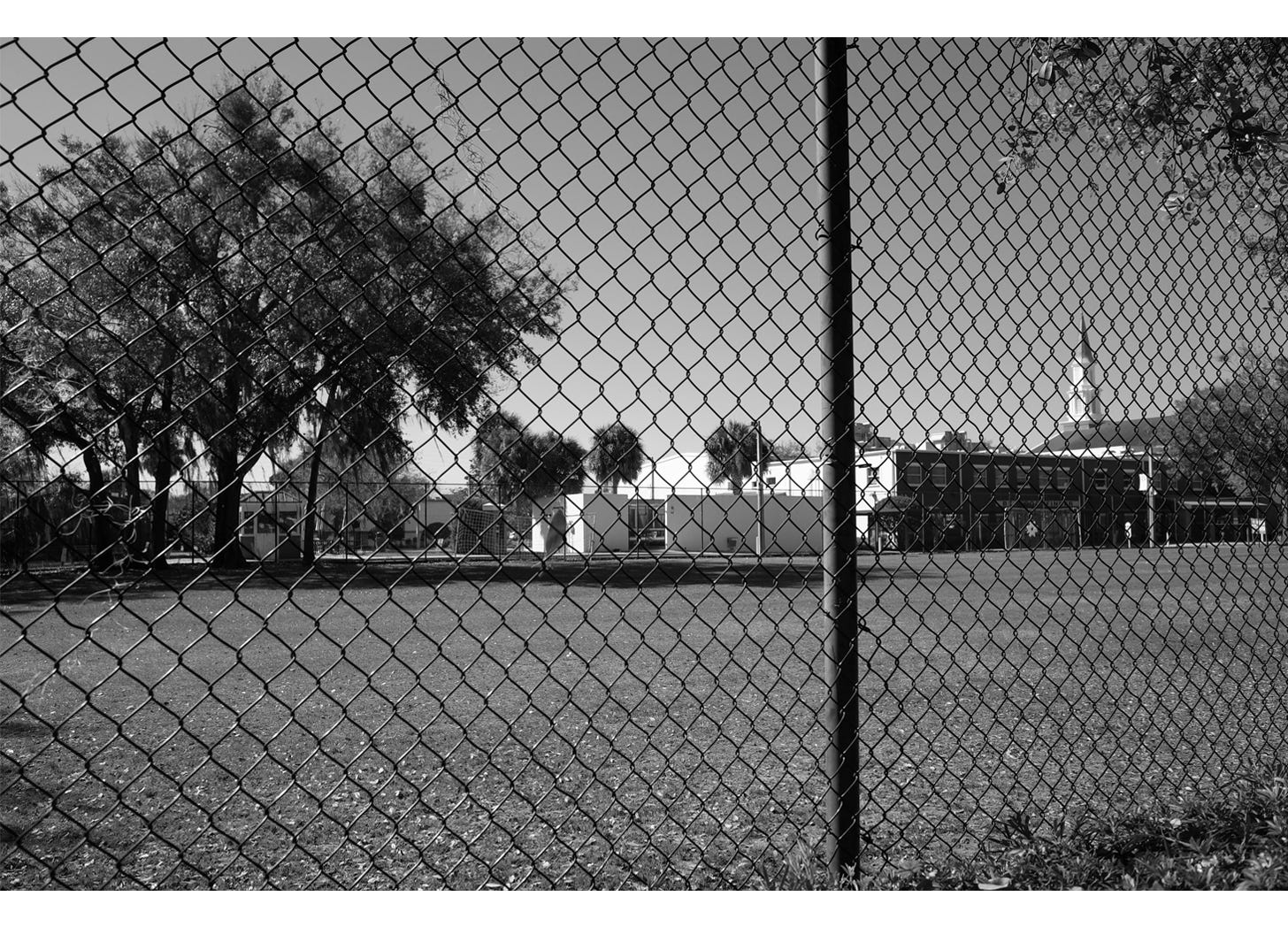 Lake Highland Prep field viewed through chain link fence with chapel in background