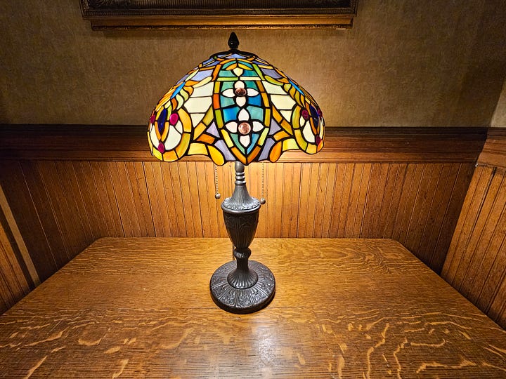 Images of the inside of Mohonk Mountain House, including a colorful Tiffany lamp, an ornate wooden fireplace with 2 portraits above, an antique clock, and a sign that says Afternoon Tea & Cookies.