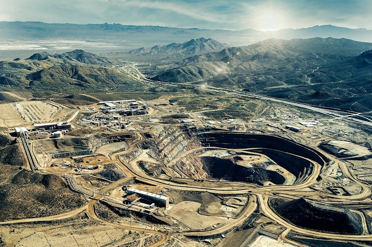 A mine and buildings with mountains in the background.