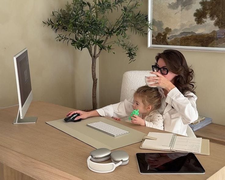 This may contain: a woman sitting at a desk with a child on her lap