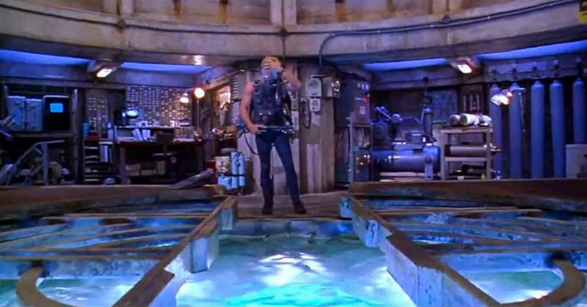 Thomas Jane in dive gear, gripping a speargun as he prepares to enter the moonpool at Aquatica.
