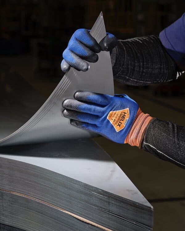 Two gloved hands peeling back sheets of steel from a stack. Two gloved hands peeling back sheets of steel from a stack.