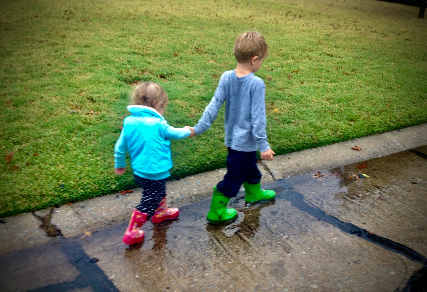 Children in boots holding hands in the rain
