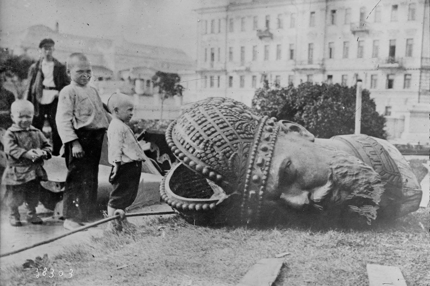 Russian children standing by the decapitated head of a statue of Tsar Alexander III during the Russian revolution, 1918.