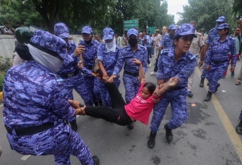 A group of security personnel carry a protester by the arms and legs