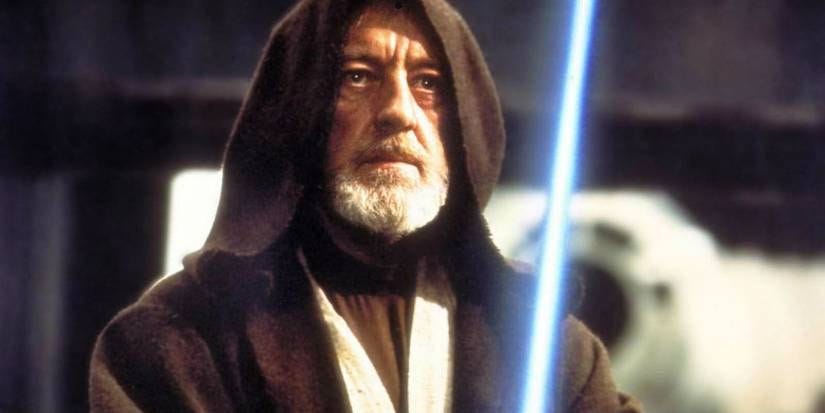 A hooded Ben Kenobi (Alec Guinness) raises his lightsaber to duel Darth Vader in A New Hope