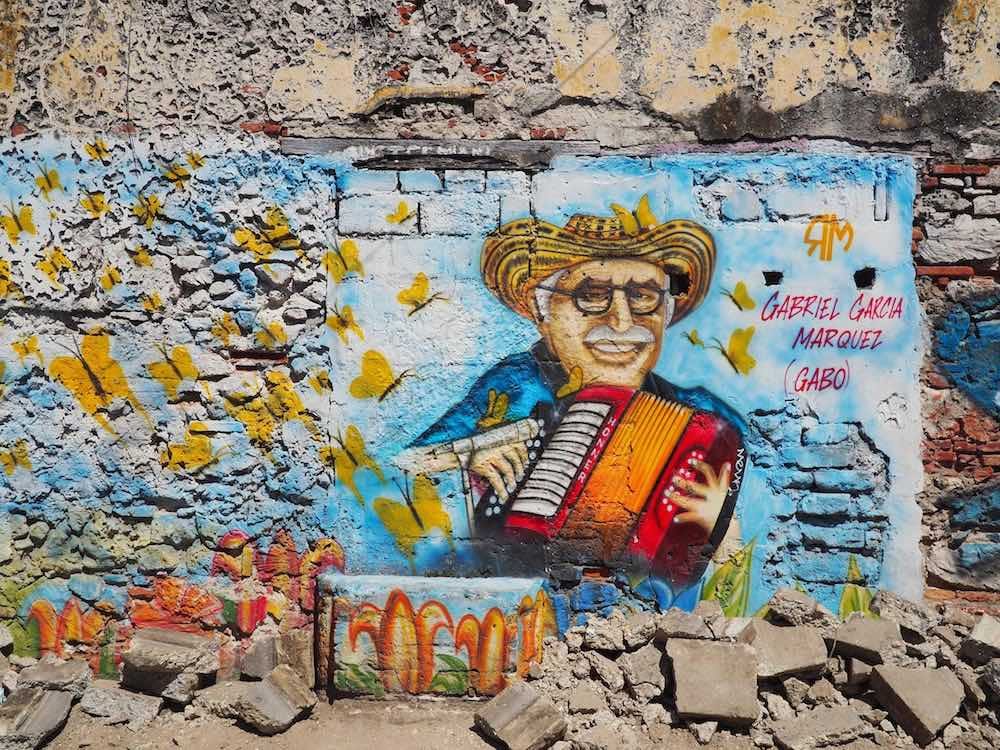 Street art - a man plays accordion on a blue wall with yellow butterflies
