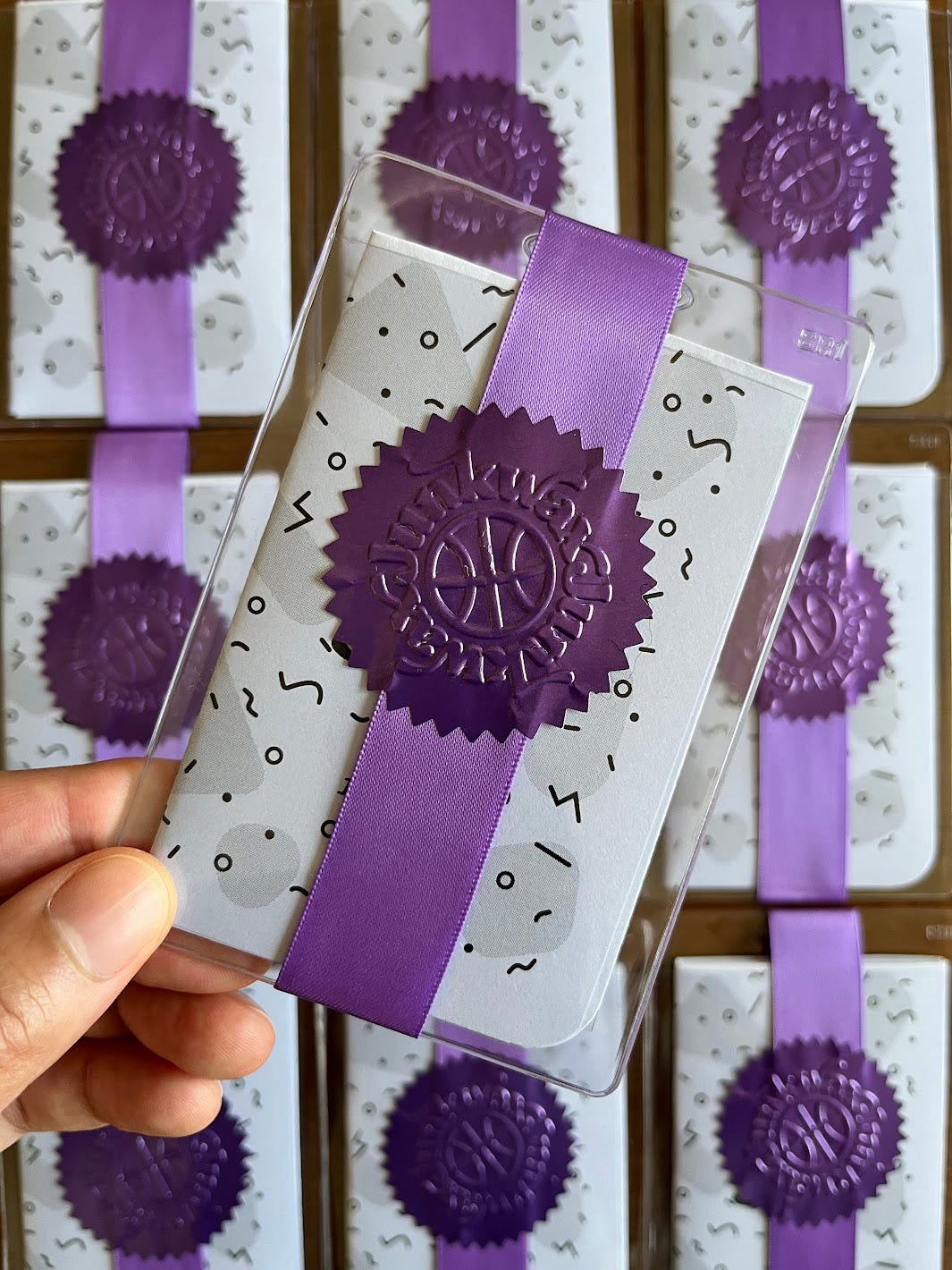 A grid of 'Junkwax' zines, individually wrapped in card protectors and purple ribbon