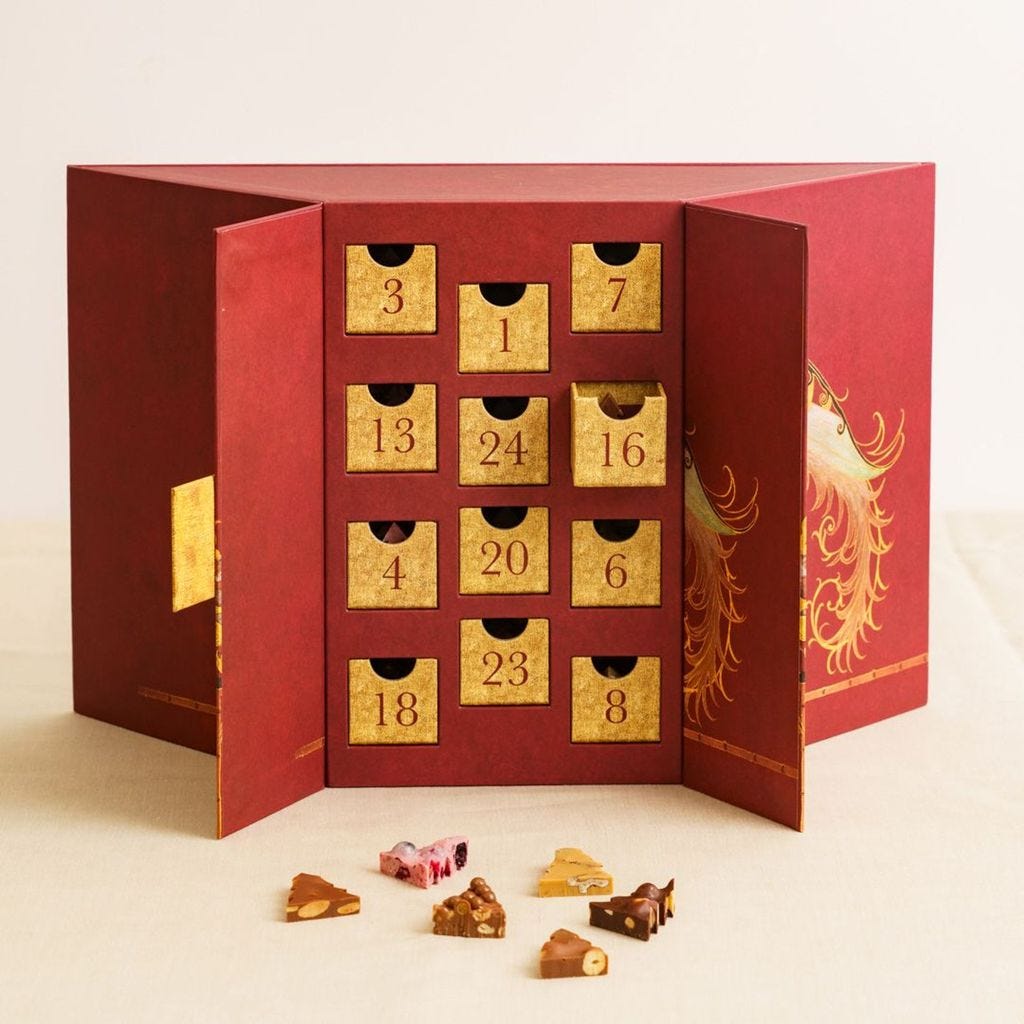 Advent calendar from Birley Bakery: Dark red angled box with gold numbered drawers. Some pieces of chocolate in front.