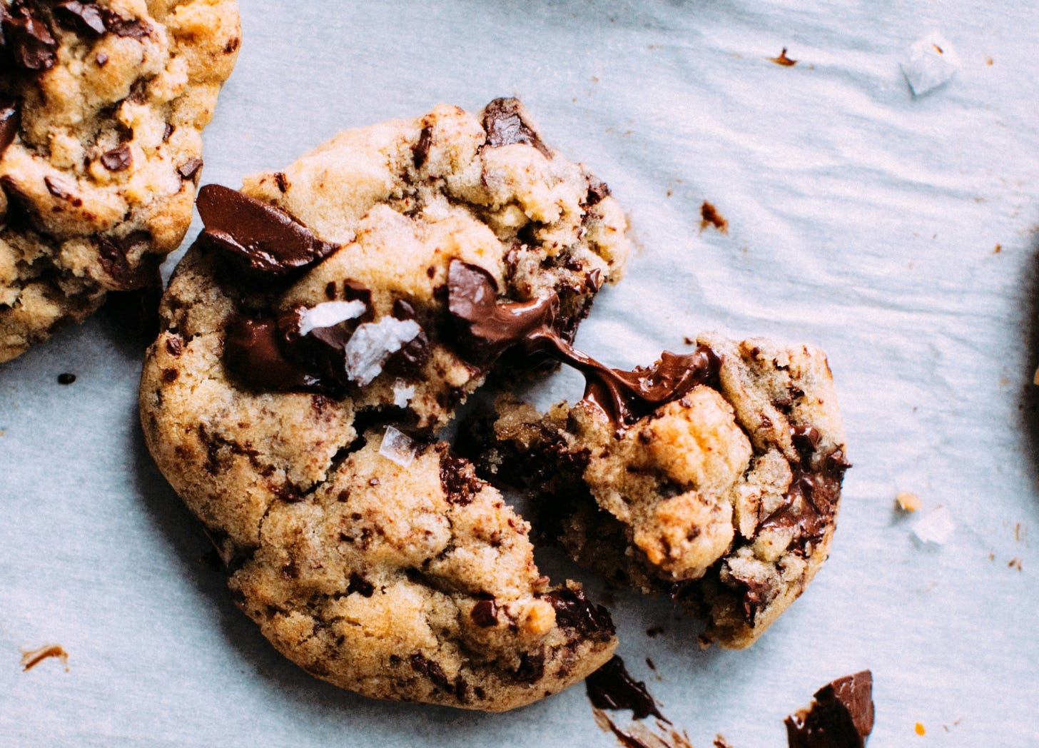 A warm chocolate chip cookie, chocolate melting at the center — the small comfort reached for at the end of a long day.