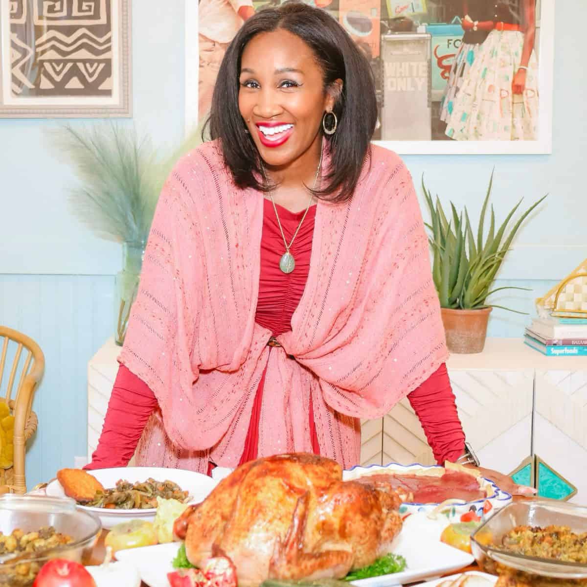 Shaunda Necole, creator of The Soul Food Pot®, smiling behind a soul food holiday table with Southern dishes, representing modern Black food storytelling, cookbook recipes, and African American culinary traditions