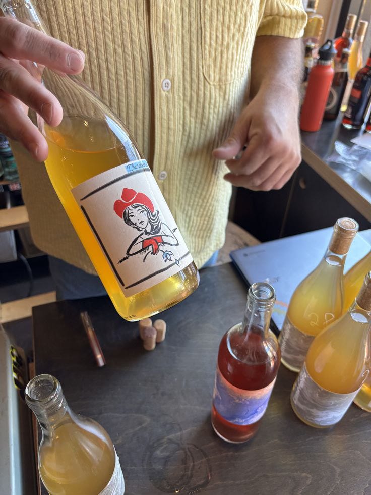 Close-up of a hand pouring orange natural wine into a glass at a Bali wine bar, showing the hazy unfiltered look of minimal-intervention wine. Close-up of a hand pouring orange natural wine into a glass at a Bali wine bar, showing the hazy unfiltered look of minimal-intervention wine.