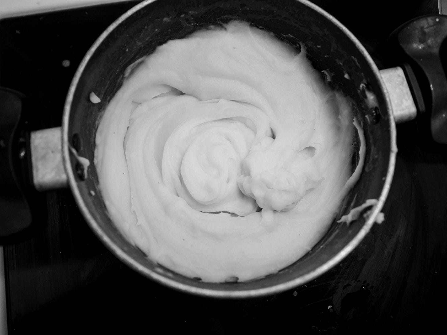 a pot of cream sitting on top of a stove a pot of cream sitting on top of a stove