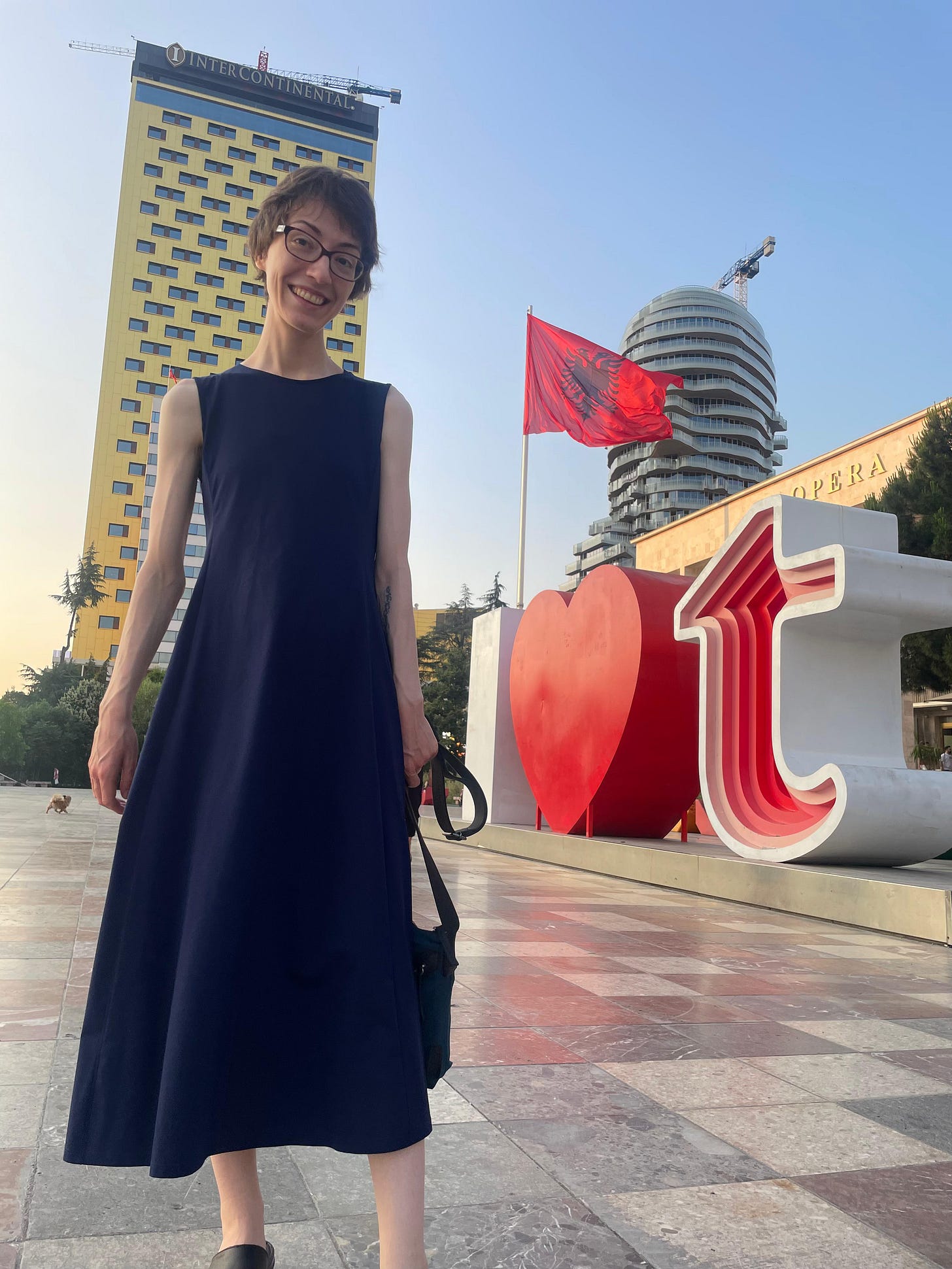 Smiling woman stands in a plaza in Albania.