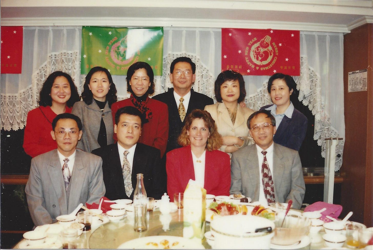 Group of ten business people--nine who are Asian and one Caucasian woman--ready to celebrate a holiday meal together.