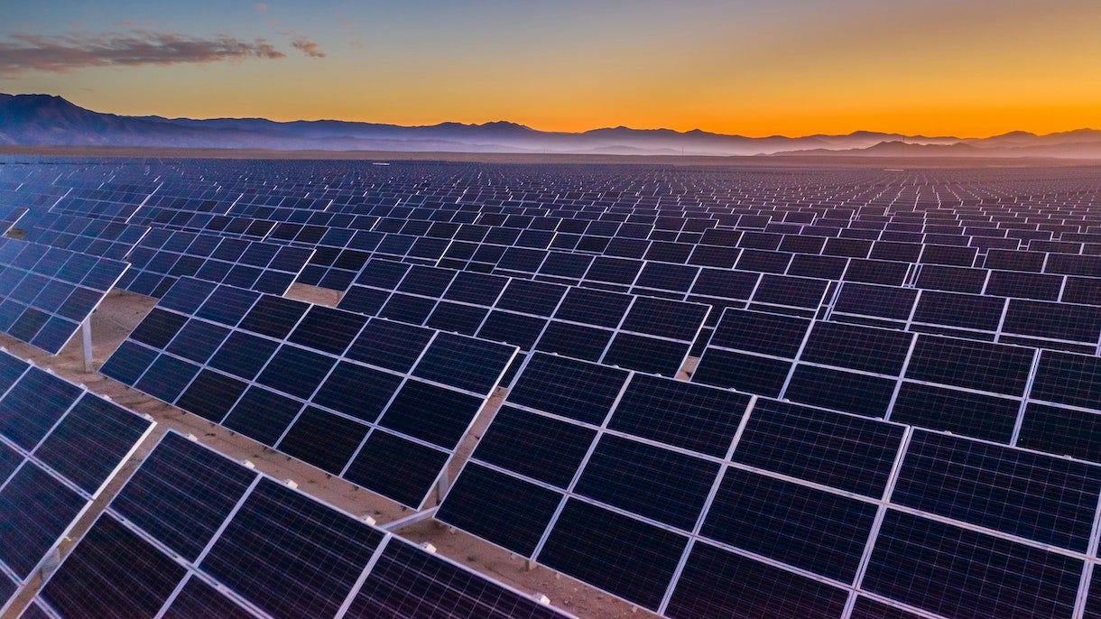 Photo depicts and aerial view of hundreds solar energy panels rows along the dry lands at Atacama Desert, Chile. Huge Photovoltaic PV Plant in the middle of the desert from an aerial drone point of view during sunset