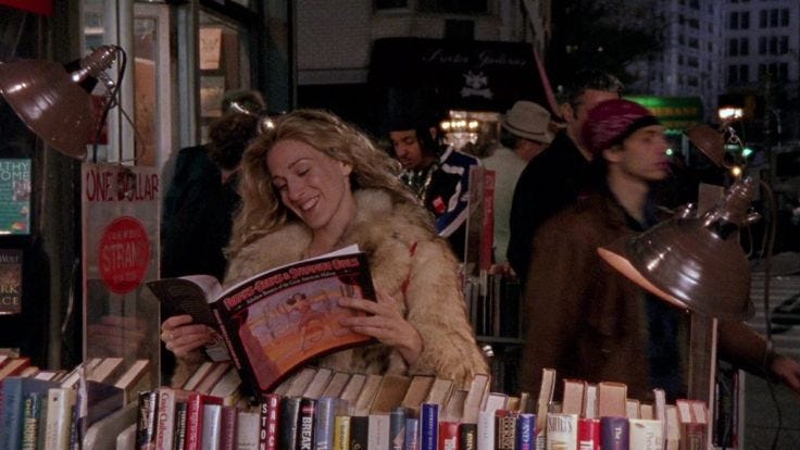 This may contain: a woman reading a book in front of a table full of books