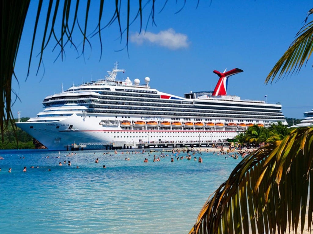 Cruise ship in port with people swimming from a nearby beach