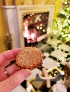 A table of colourful sweets in jars and a small mince pie in front of an open fire.